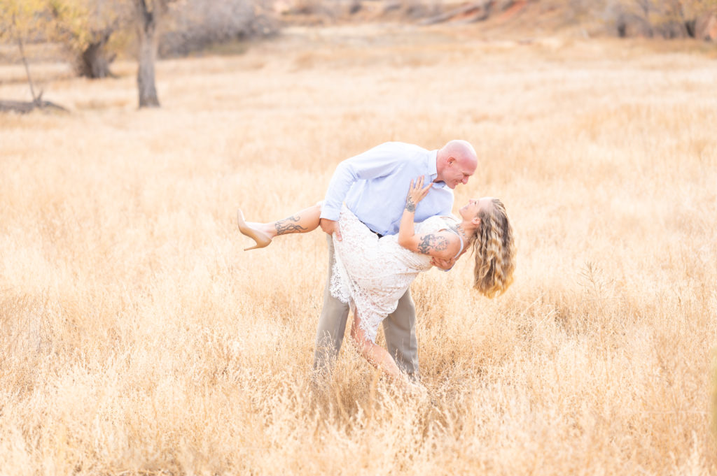 Groom dipping his bride and giving her a kiss in the open field landscape at Red Rock Open Space