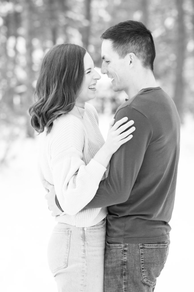 Couple laughing together during photoshoot in the snow at fox run regional park. 