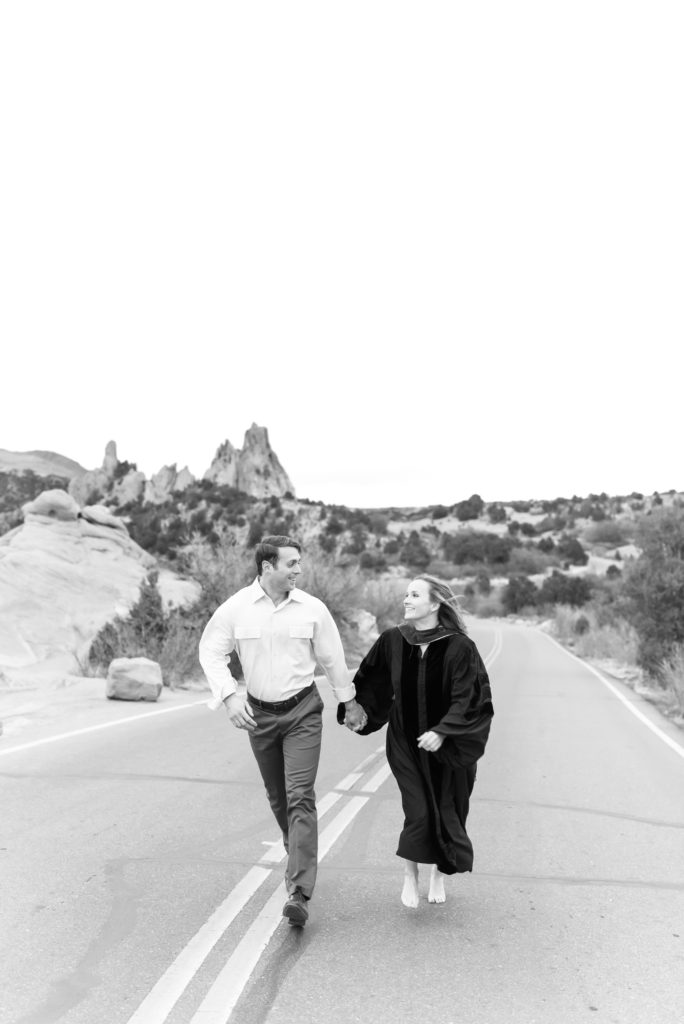 Couple running across the road at high point overlook within garden of the gods park 
