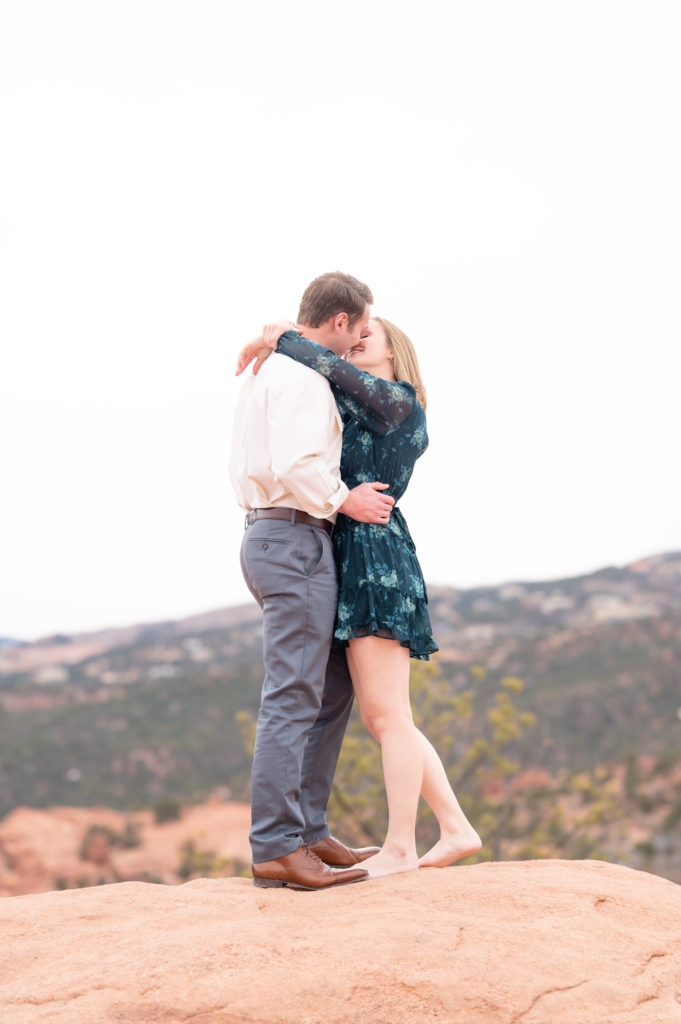 Couple kissing on top of a rock at high point overlook within garden of the gods park at Colorado Springs 