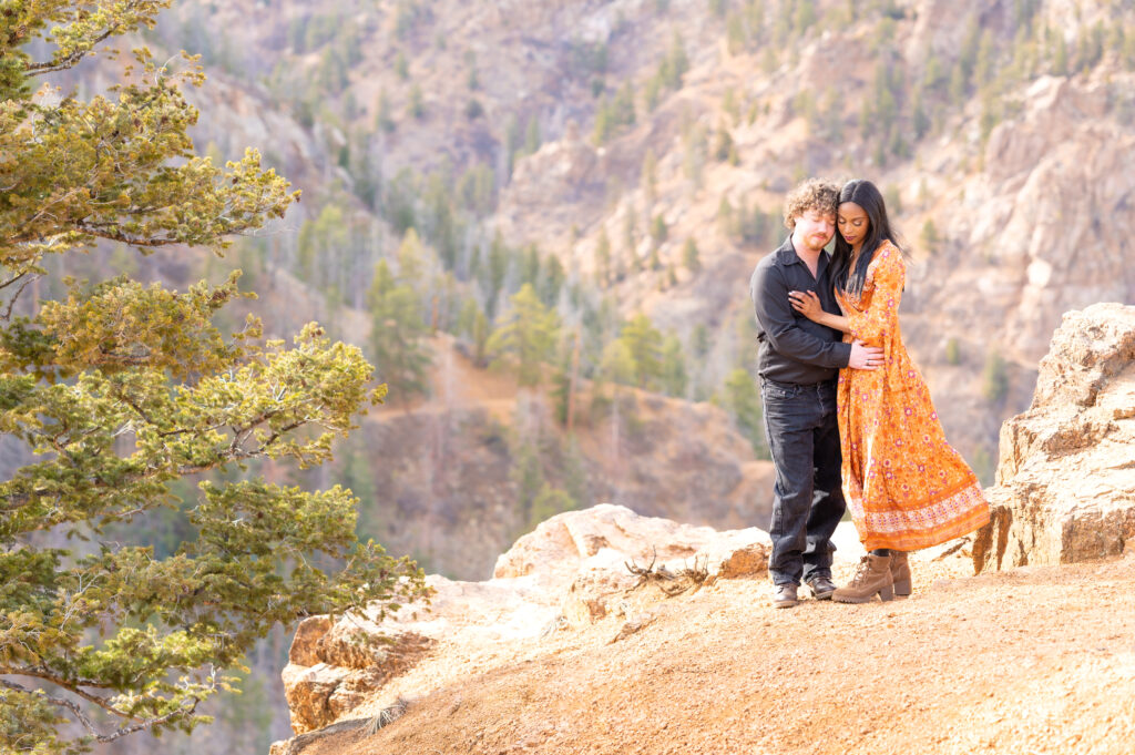 Couple hugging one another closely with mountain backdrop