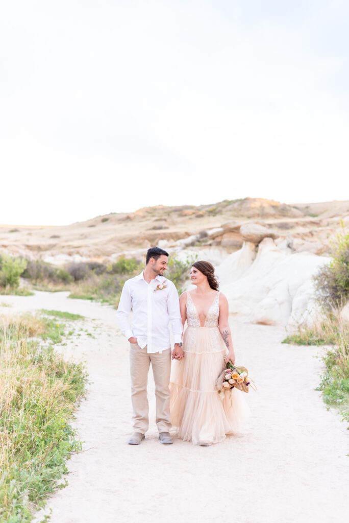 Bride and groom walking together holding hands on trailhead