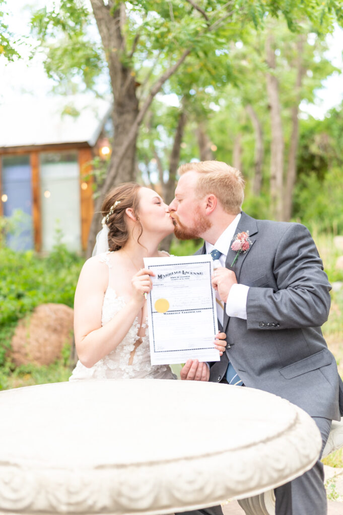 Bride and groom kissing one another while signing their colorado marriage license