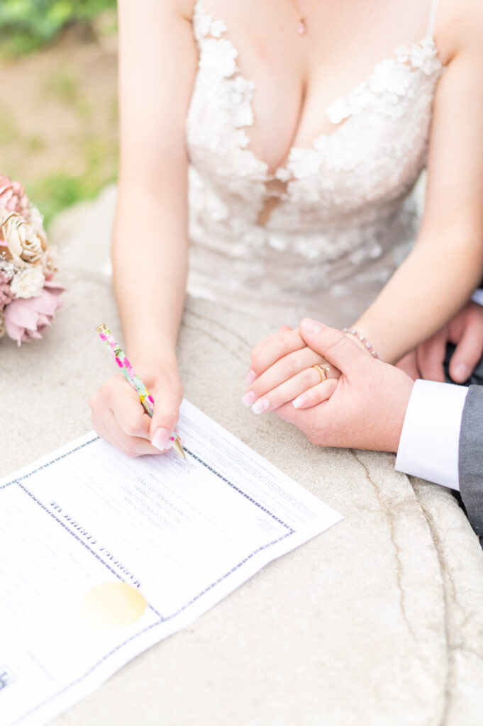 Bride and groom signing their marriage license together in colorado