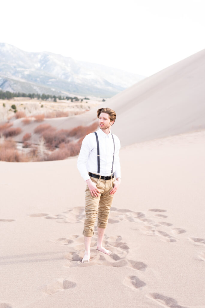 groom standing with hands in his pockets at the great sand dunes in colorado