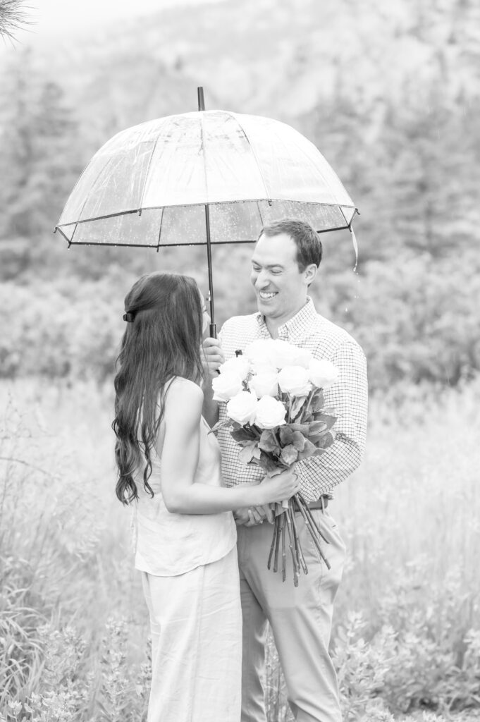 Colorado Springs Photographer capturing couple laughing together while standing under an umbrella 