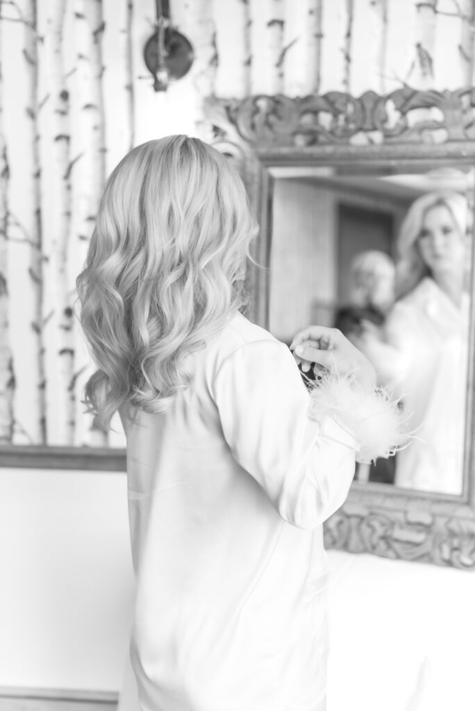 Bride getting ready on her wedding day looking into the mirror fixing her hair