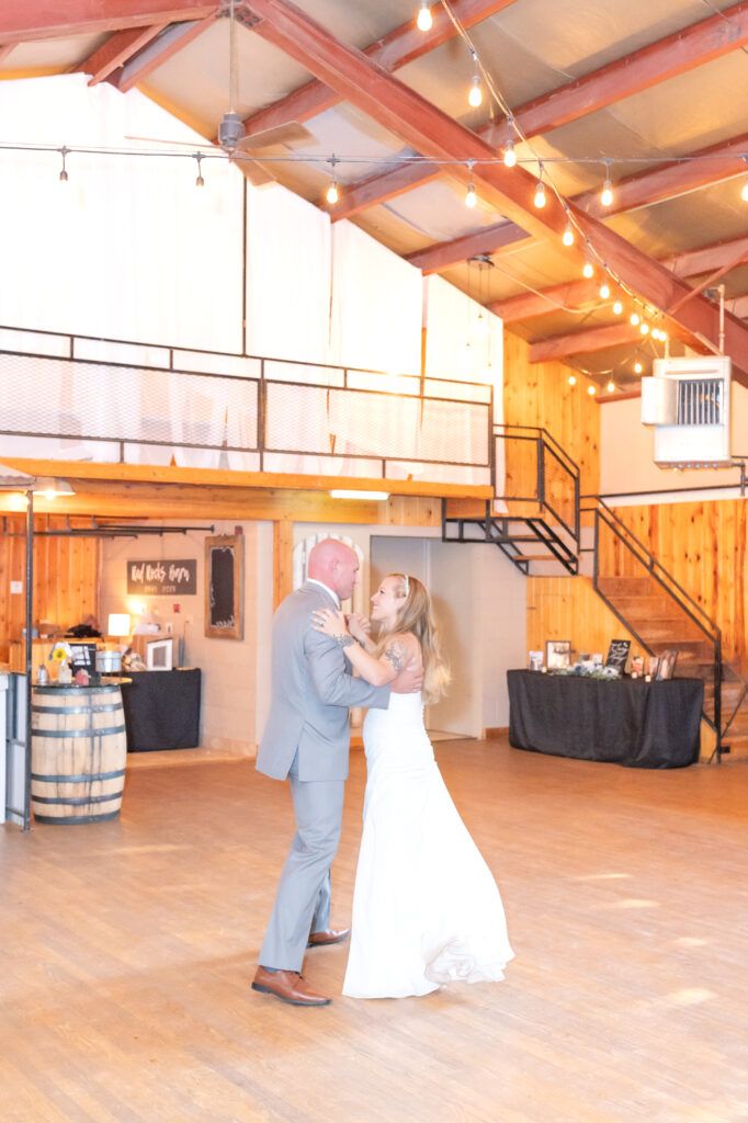 Bride and groom sharing their first dance together as husband and wife at red rocks barn wedding venue in Colorado Springs 