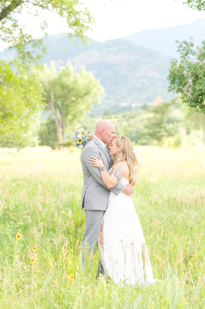 Groom giving his bride a forehead kiss on their wedding at red rocks barn wedding venue in Colorado Springs 