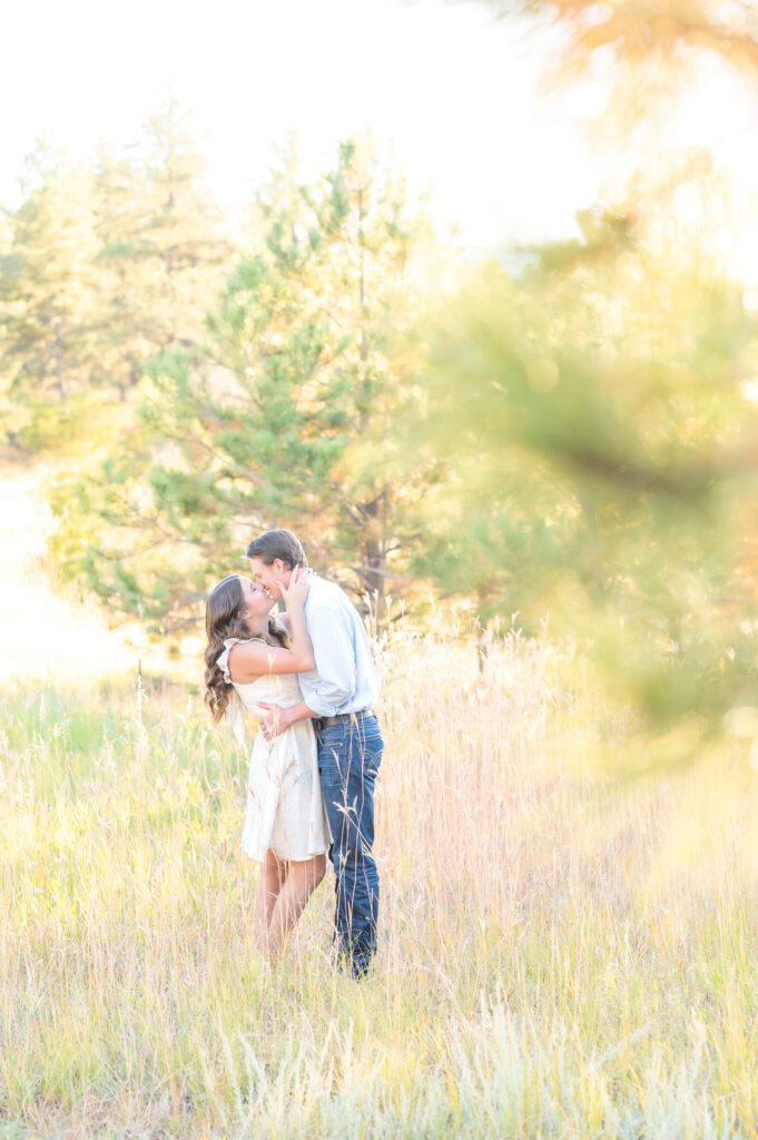 Couple kissing in the open grass field during fall season at Dawson Butte Open Space in Colorado