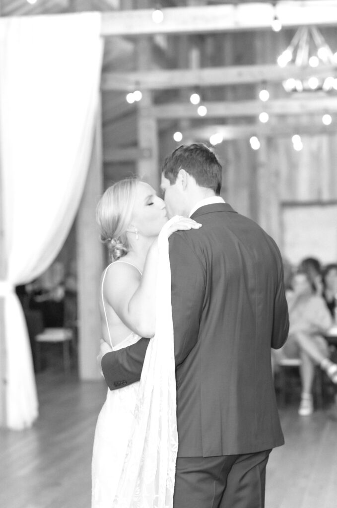 Bride and groom sharing a kiss together during their first dance together as bride and groom