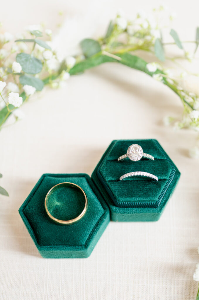 Wedding rings in green velvet case with baby's breath arched above them