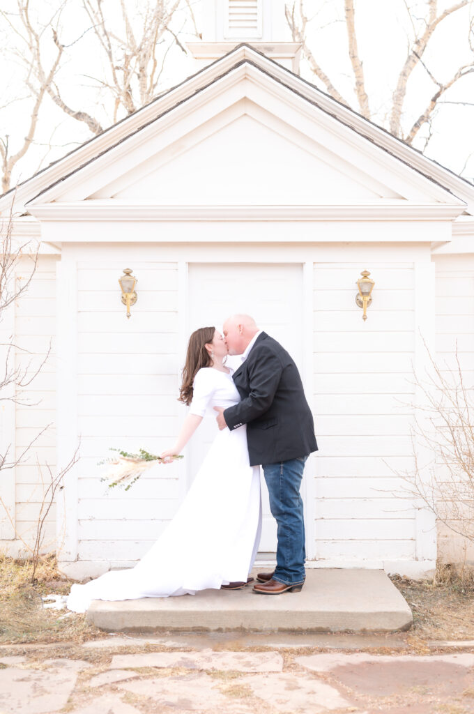 Groom dipping his bride for a kiss in front of the American Mother's Chapel Colorado Springs