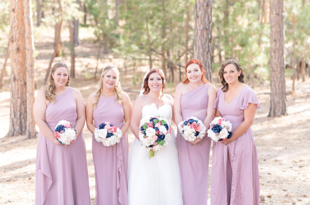 Bride standing next to her bridesmaids while holding their flower bouquets at Black Forest by Wedgewood