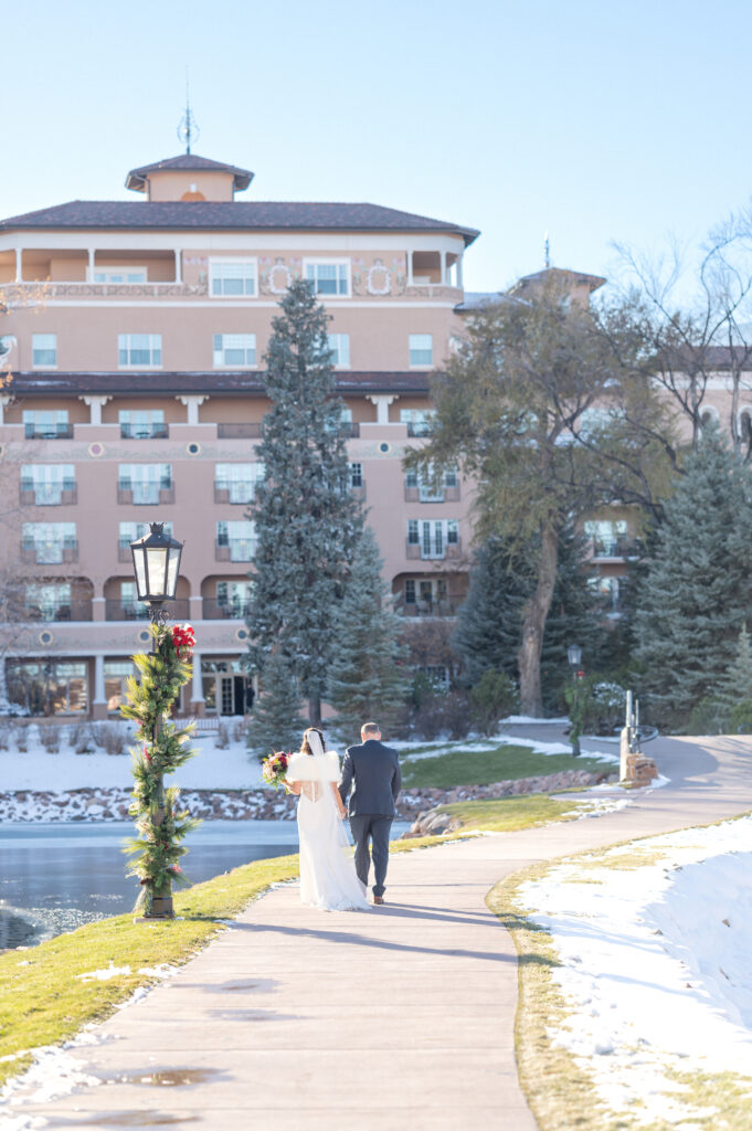 Bride and groom walking along the path holding hands at The Broadmoor wedding venue in Colorado Springs
