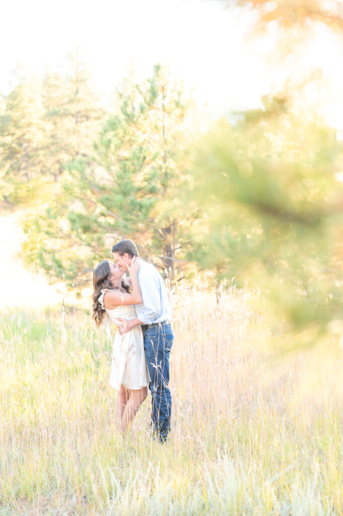 Couple kissing in a meadow during their Colorado engagement photoshoot