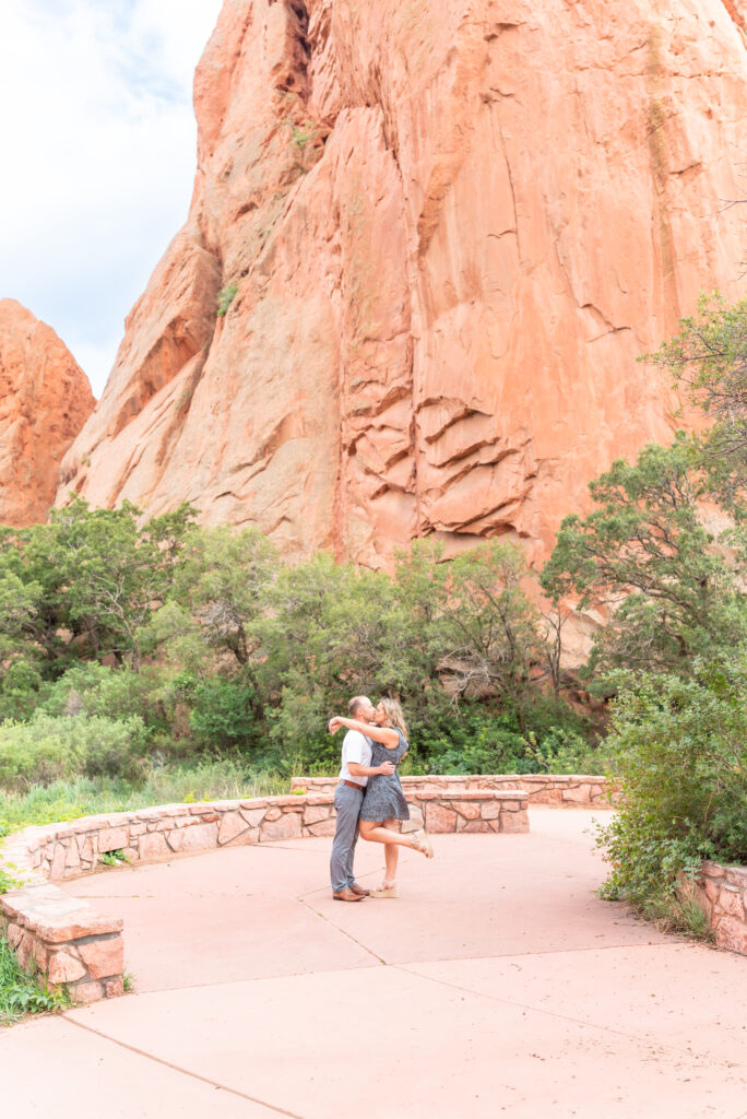 Engaged couple exchange a kiss against a backdrop of red rock in one of Colorado's most popular spots for engagement photos