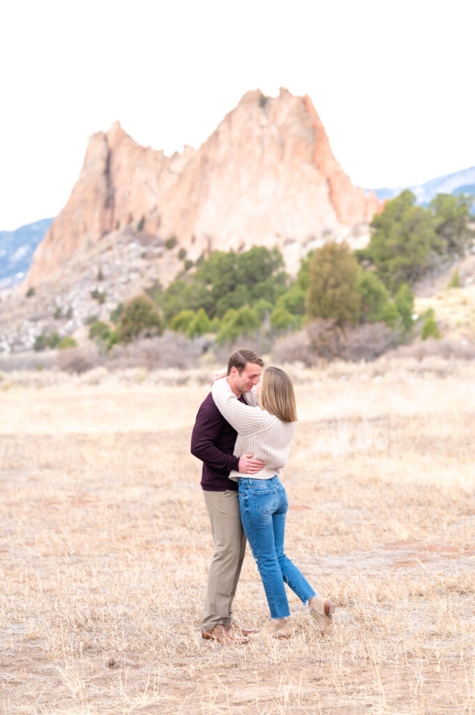 Woman wraps her arms around her fiance's neck as they exchange a kiss during their engagement photos in Colorado
