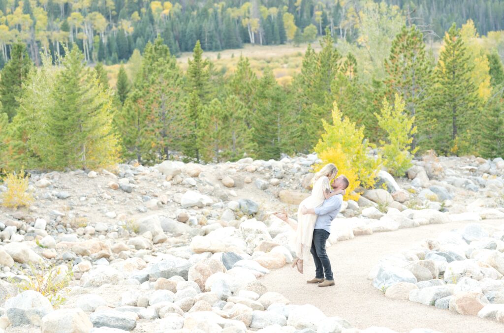 Man and woman embrace on a rocky path in the mountains during their engagement photos in Colorado