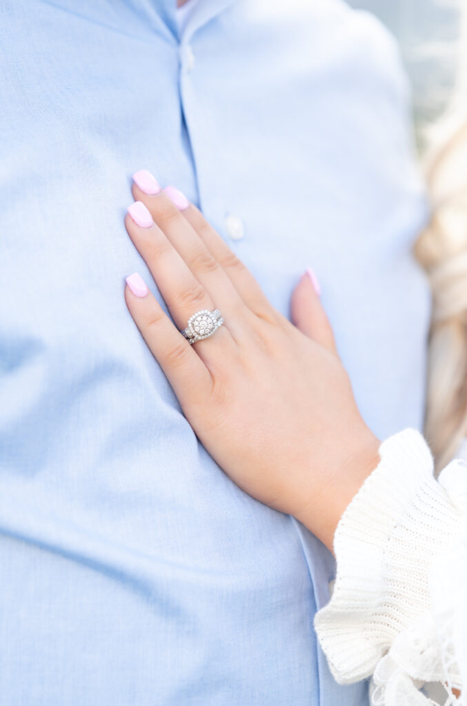 Closeup of woman's hand, with engagement ring, resting on her fiance's chest