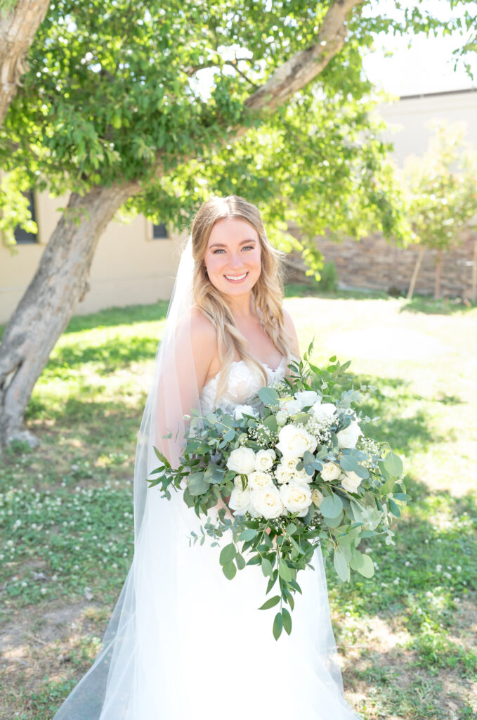 Bride holding her bridal floral bouquet and smiling at the camera