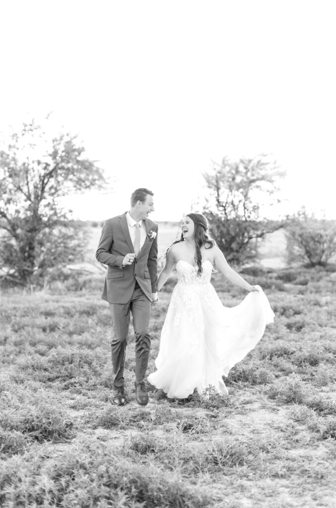 Bride and Groom running together in a field while holding hands during their Colorado wedding celebration 