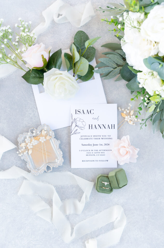 Wedding flat lay detail photo of wedding invitation suite with greenery and white florals