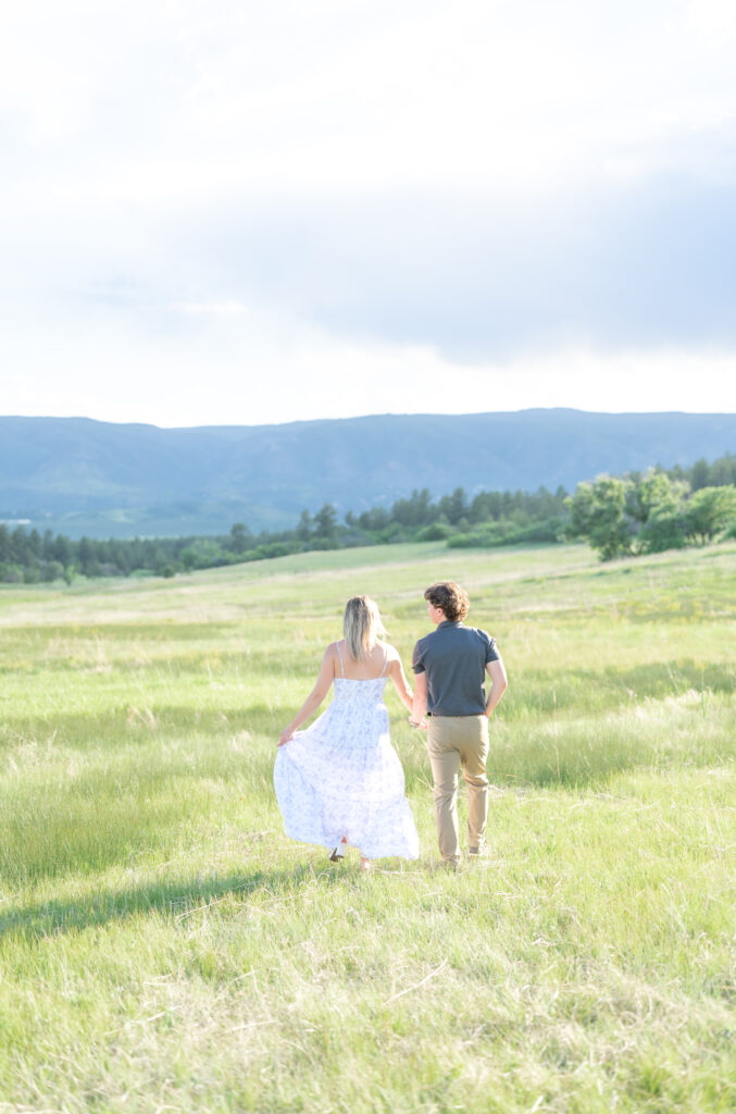 Couple walking out into the open meadow field looking together at the mountains at Dawson Butte
