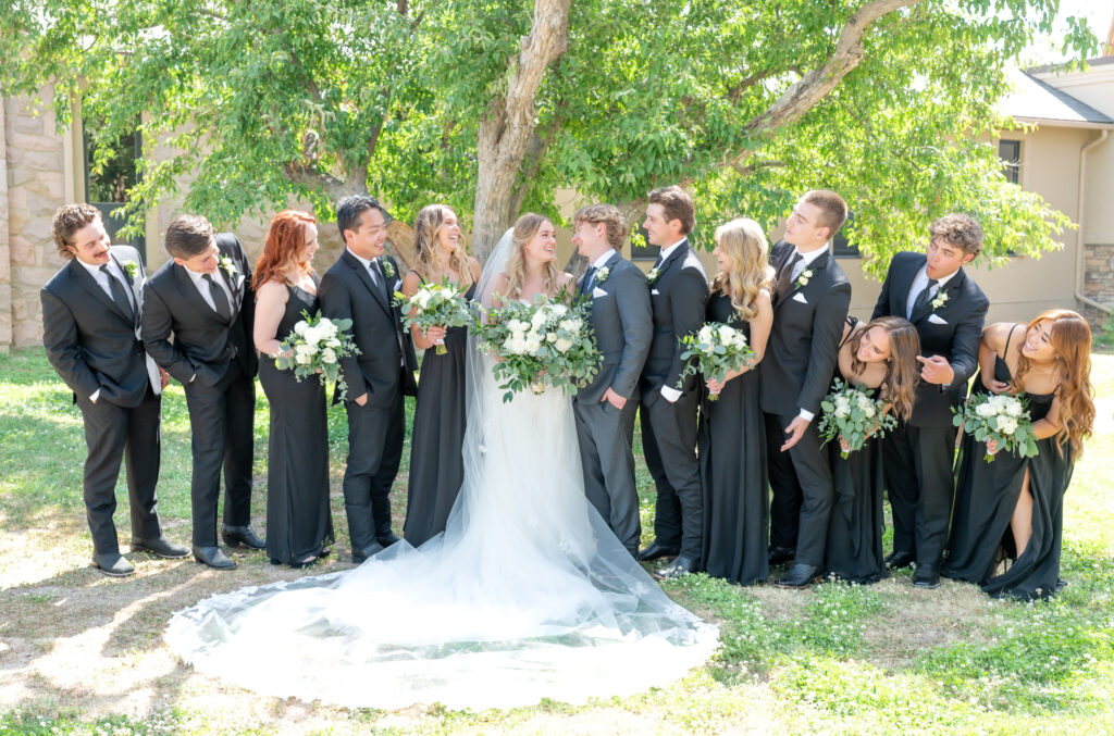 Bride and groom smiling at each other while the rest of the wedding party leans in to look at them