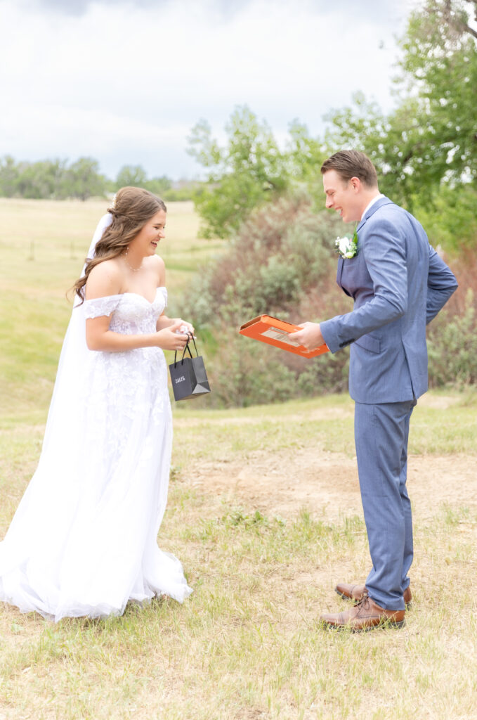 Bride and groom laughing and smiling together while exchanging their gifts on their wedding day in Colorado