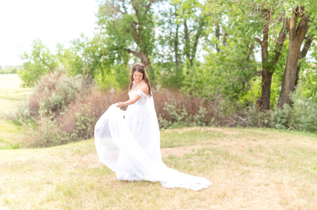 Bride standing in open field twirling her dress side to side 