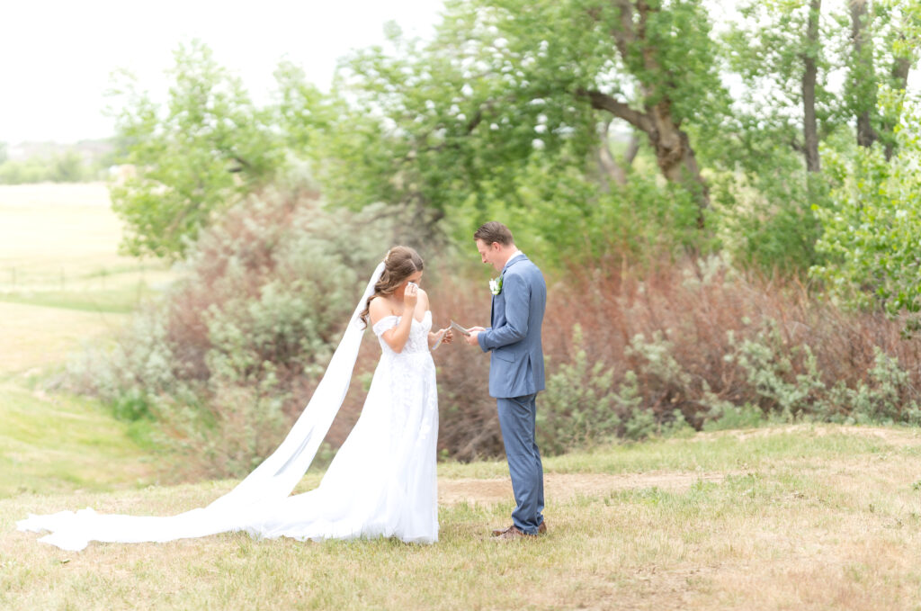 Bride and groom standing in open field exchanging their vows during their first look on their colorado wedding day