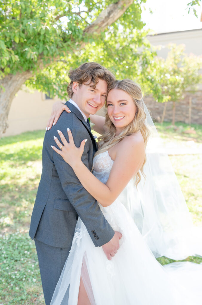 Bride and groom leaning for hug together and smiling towards the camera