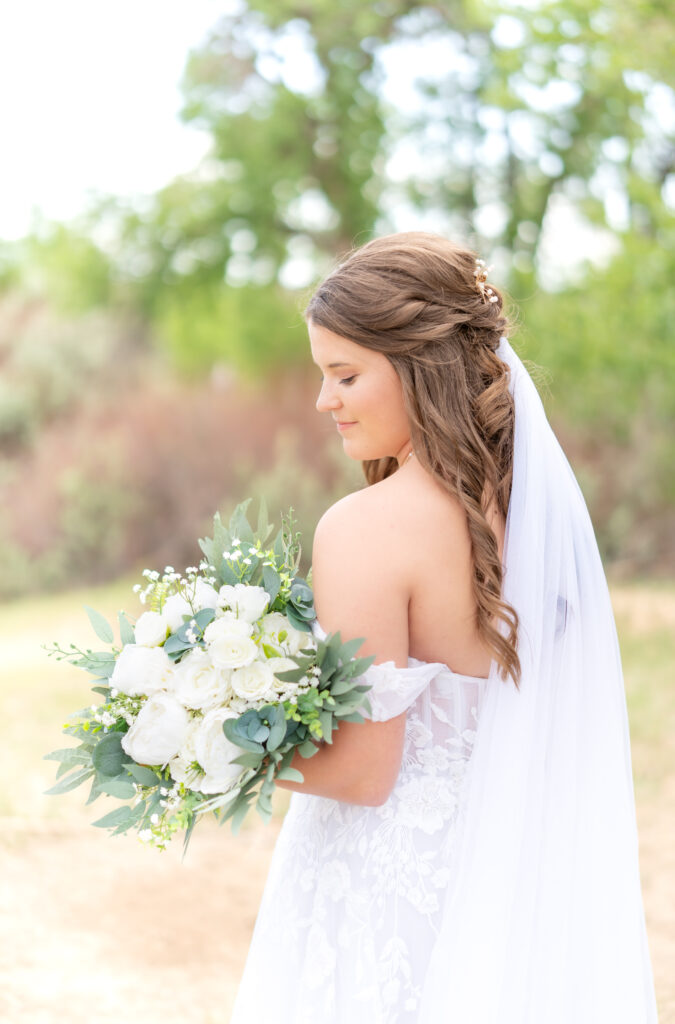 Bride looking down over her shoulder while holding her bridal bouquet on her wedding day in Colorado