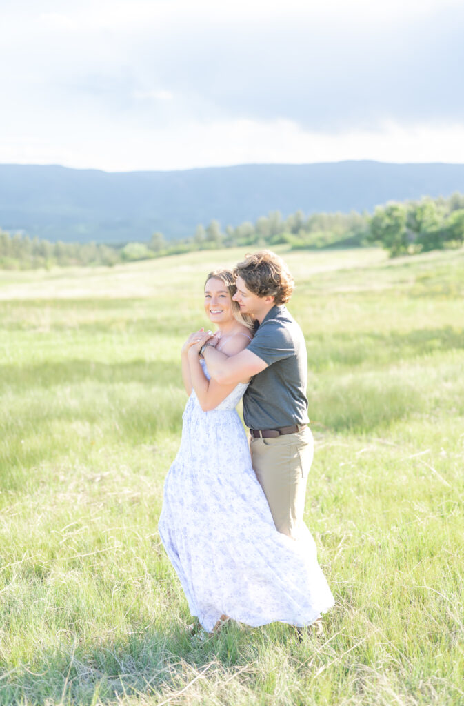 Couple sharing an intimate bear hug while standing in an open meadow field at Dawson Butte Open Space