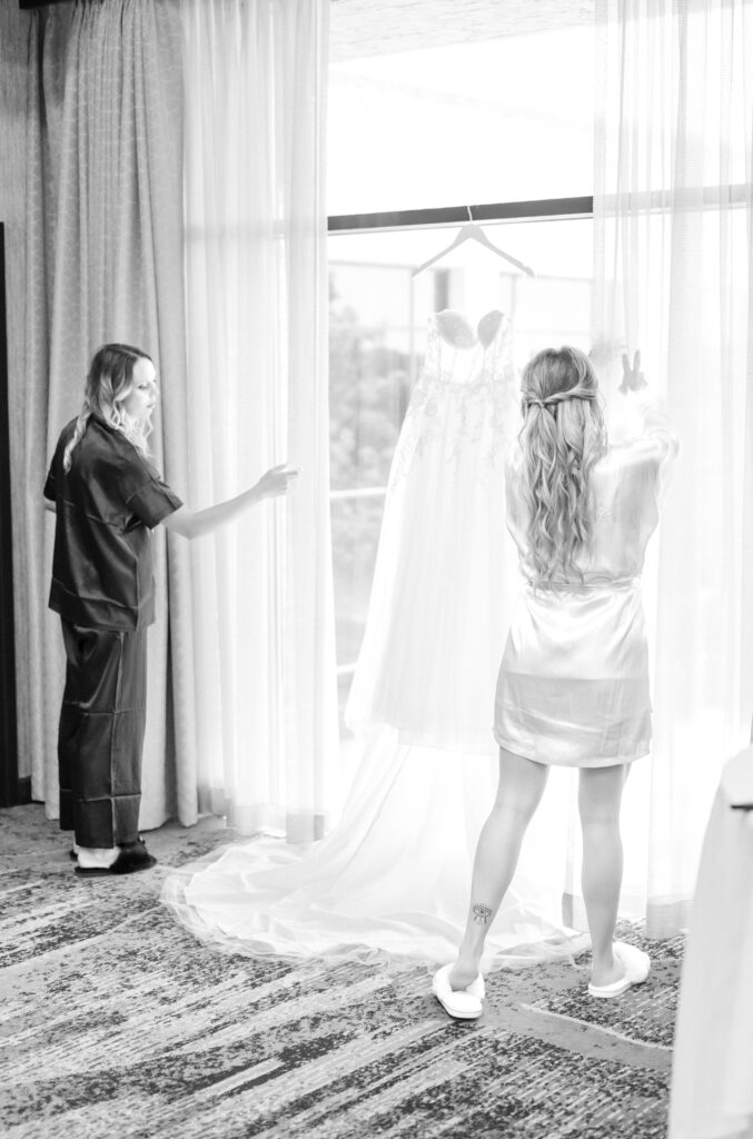 Bridesmaid helping the bride hang her dress up on a hanger on her Colorado wedding day