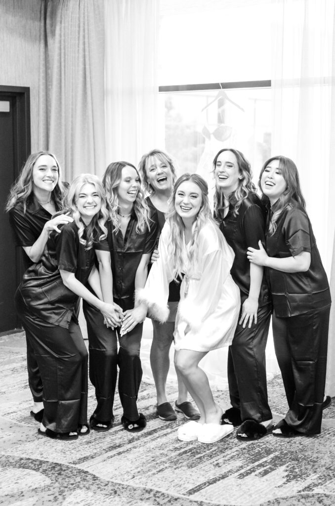 Bride with her bridesmaids in their getting ready attire smiling and laughing together 