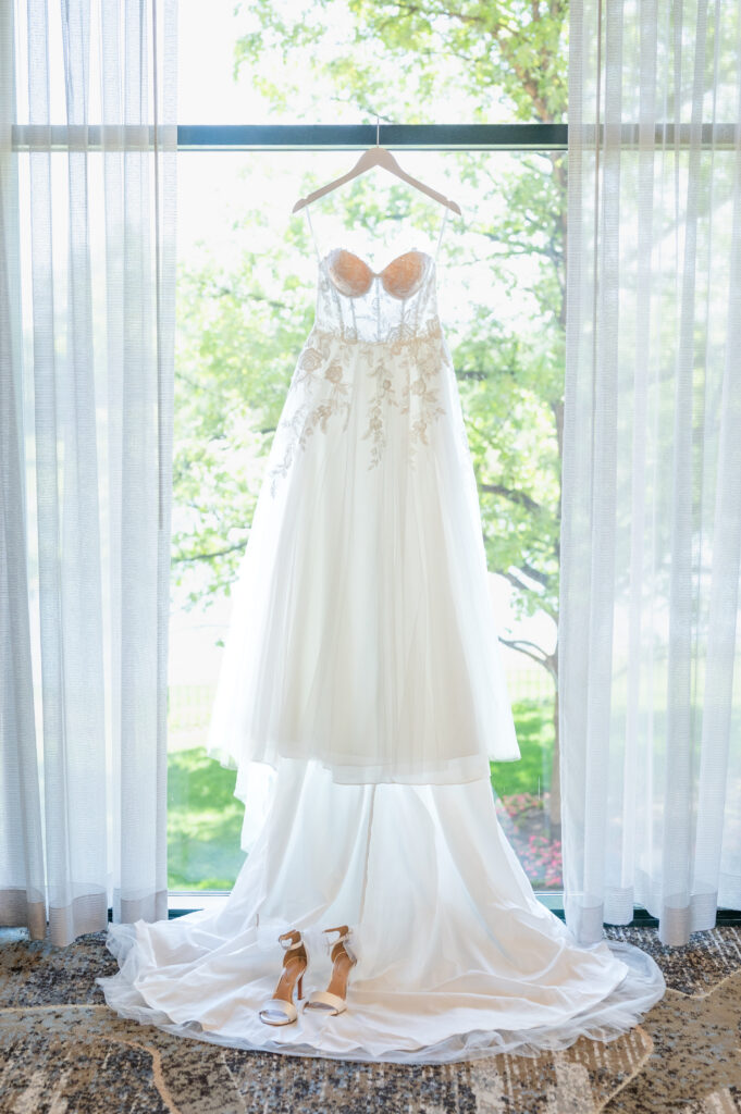 detail photo of the bride's wedding dress hanging on a white hanger in hotel room at The Denver Inverness