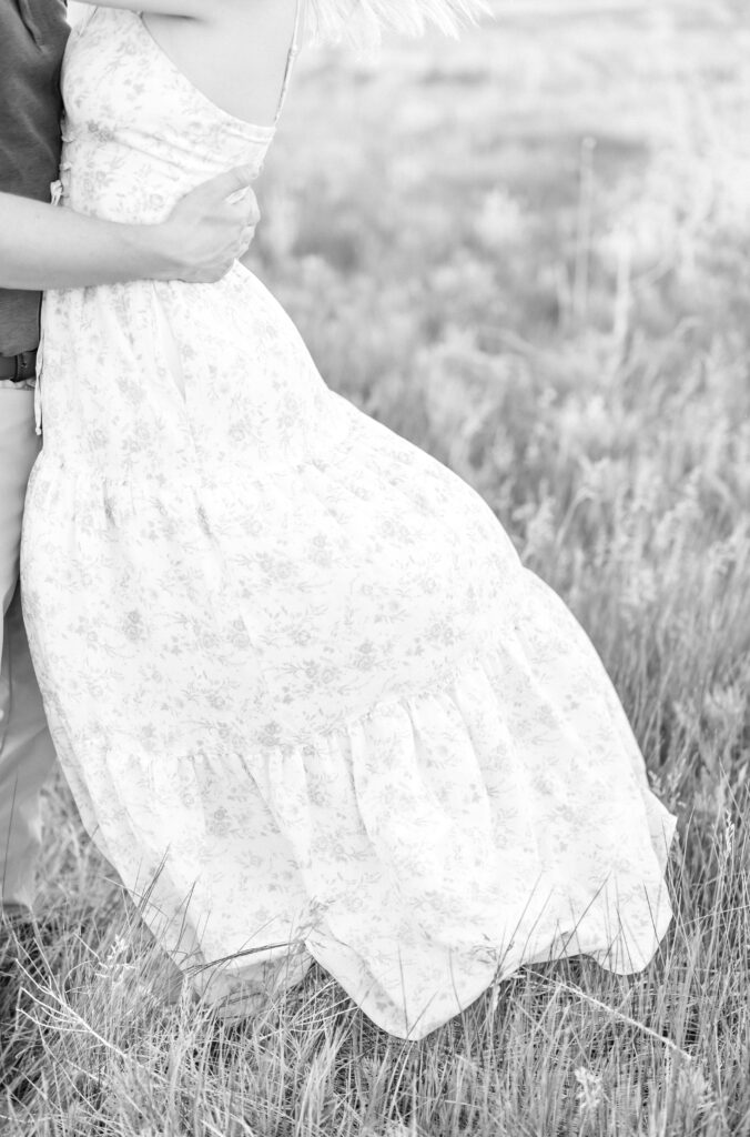 Detail photo of couple holding each other while the girl's dress is blowing in the wind