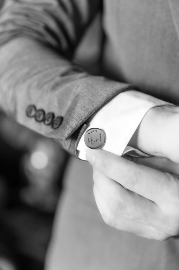 Detail close up photo of the groom putting on his cufflinks on the sleeve of his shirt