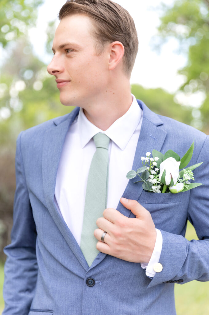 Groom looking off to the side while holding his lapel of his suit jacket 