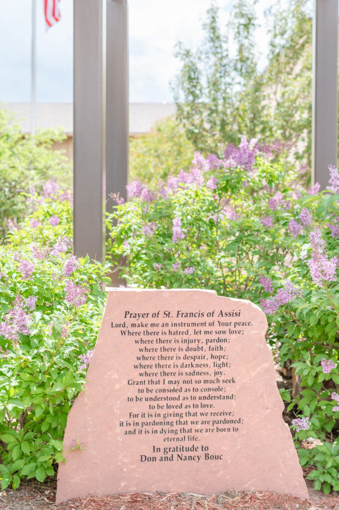 detail photo of church signage and purple florals behind 