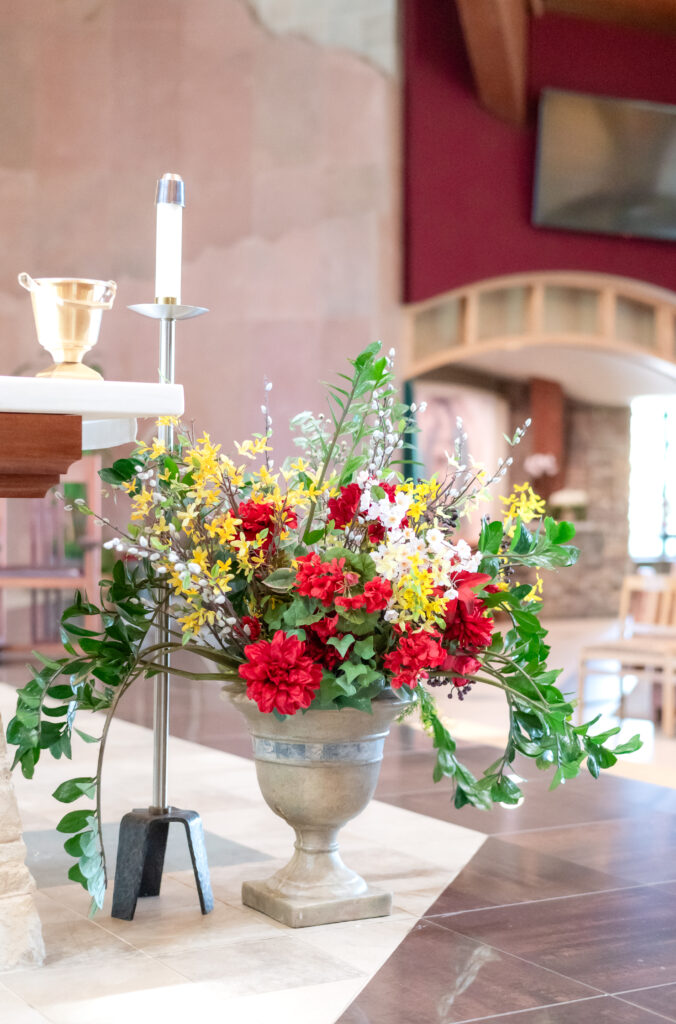 photo of colorful floral plant at front of the altar inside of a Catholic Church for a wedding ceremony 