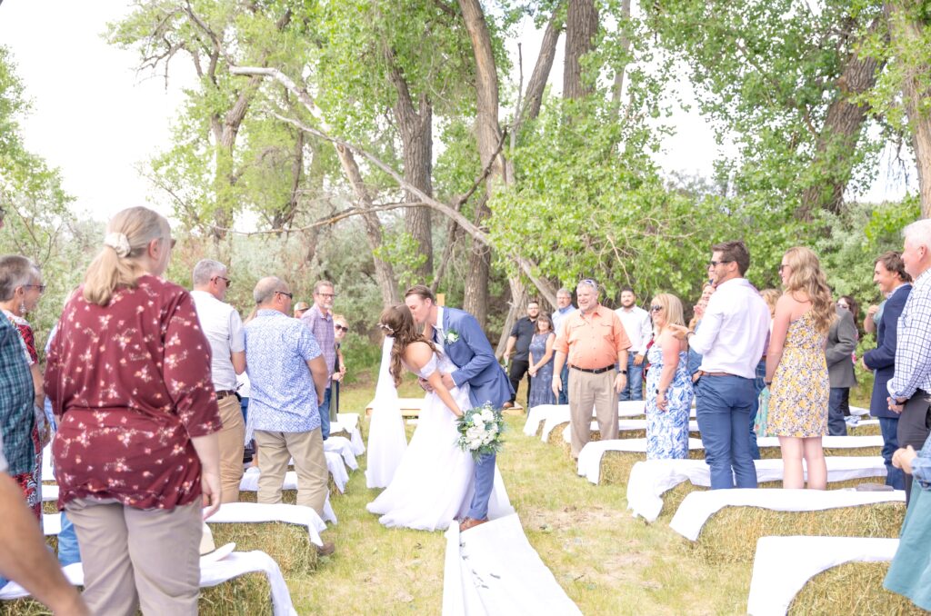 Bride and groom sharing a romantic dip kiss down the aisle exiting their wedding ceremony 