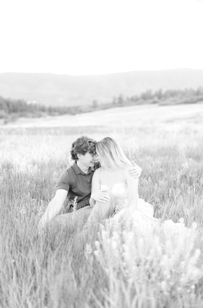 Couple sitting down together for an intimate hug while sitting in a field of summer wildflowers at Dawson Butte 