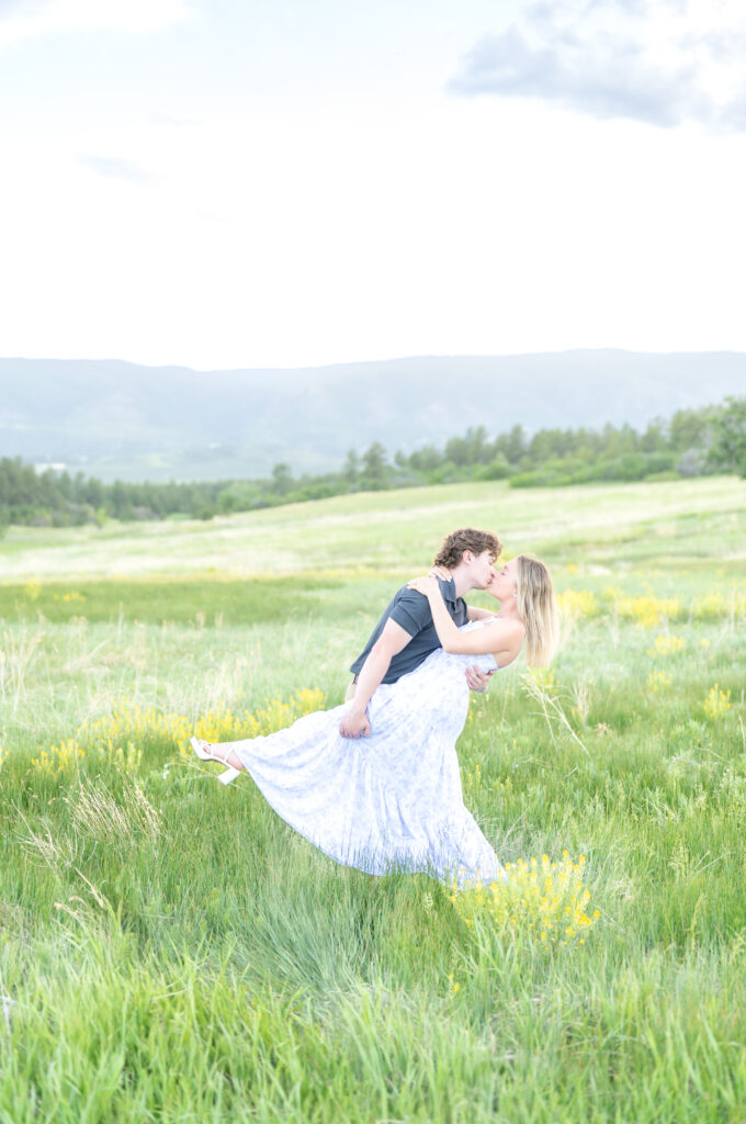 Couple sharing a romantic dip kiss in open field with yellow flowers at Dawson Butte Open Space