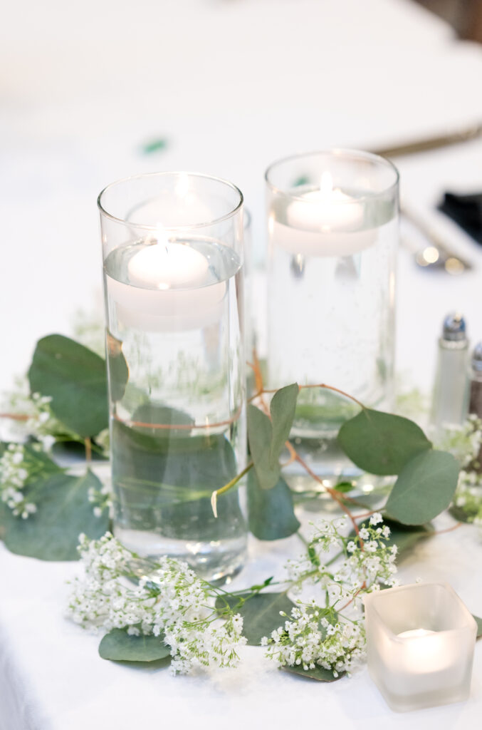 greenery wrapped around clear white candles sitting on table