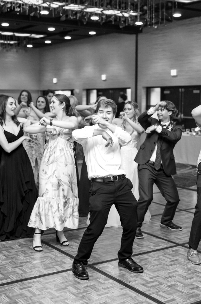 Picture of wedding guests waving his hands in the air dancing during reception