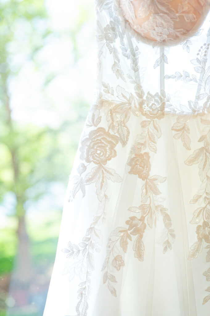 close detail photo of bride's wedding dress and showing floral detail design on the dress