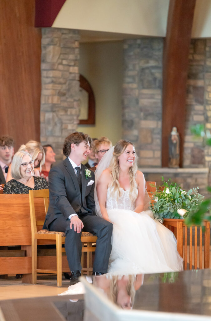 photo of the bride and groom sitting up at the front of the church during their wedding catholic ceremony